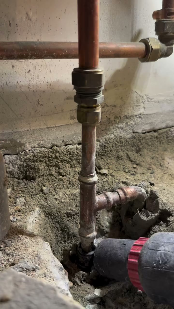 Koperen waterleidingen met knelkoppelingen, vrijgemaakt in een muur tijdens een verbouwing